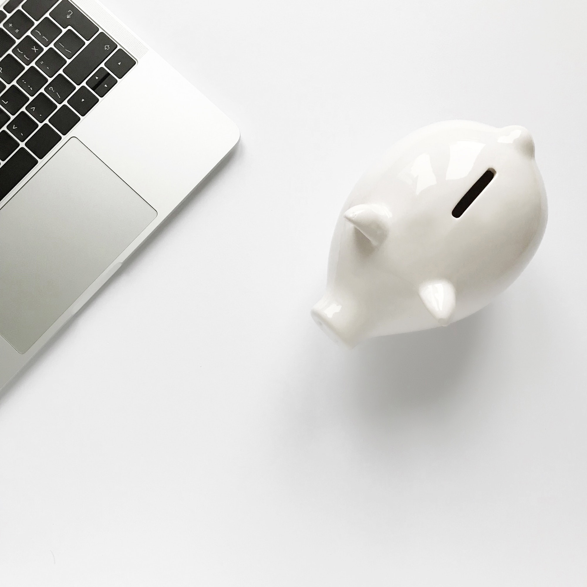 Top view piggy bank money box cash and best laptop on white background desk top at natural light