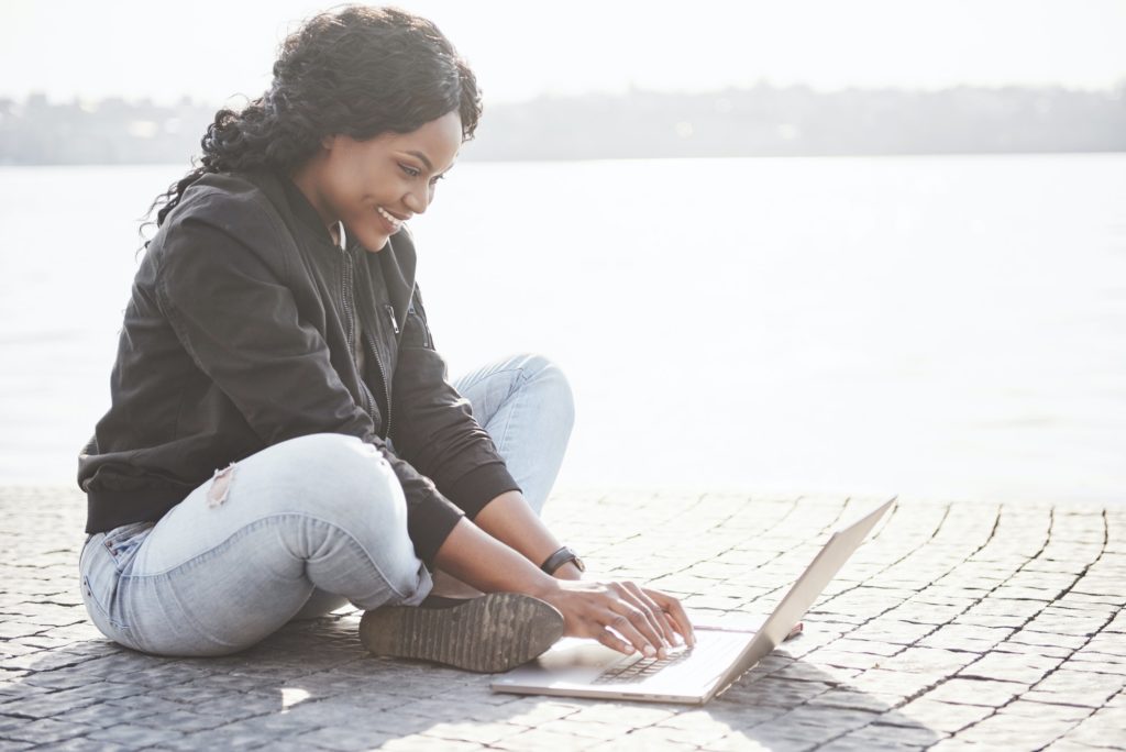 Young woman on the street working on laptop